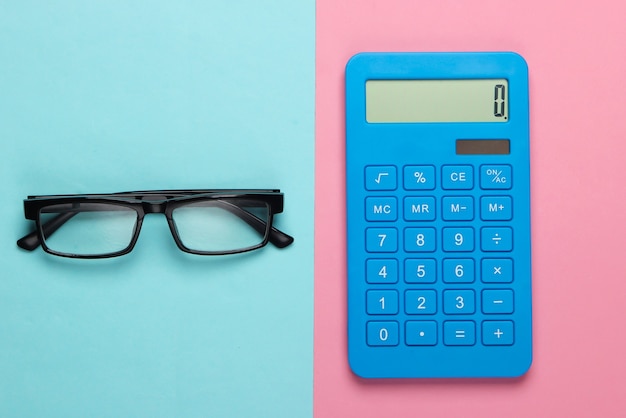 Kalkulator i okulary na niebieskim pastelowym kolorze. Koncepcja sekretarz, ekonomista lub pracownik biurowy.