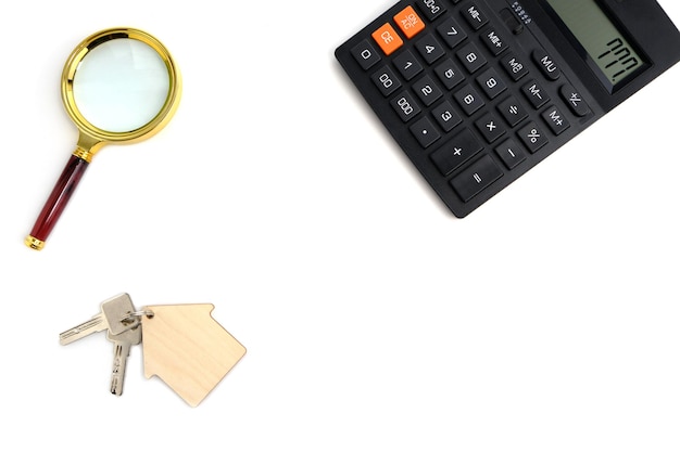 Kalkulator, lupa i klucze do domu. Koncepcja kupna i sprzedaży mieszkań, kredytów hipotecznych i wynajmu domu lub mieszkania.