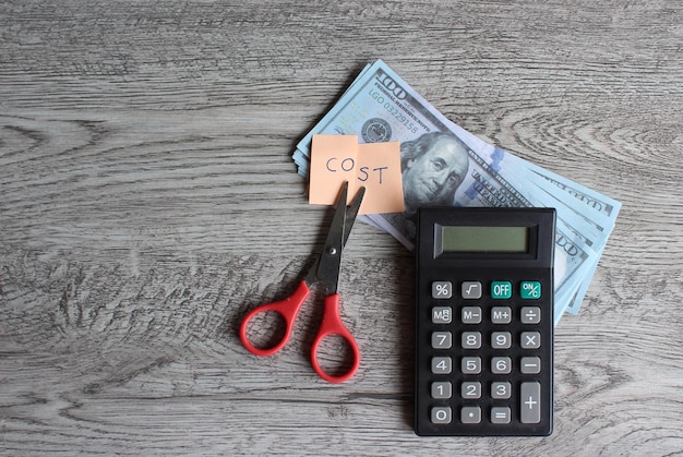 Kalkulator nożycowy pieniądze i notatka z tekstem KOSZT Cięcie kosztów finansowych koncepcja redukcji wydatków