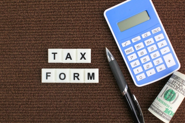 Kalkulator pióra i pieniądze papierowe z koncepcją płatności podatku w postaci formularza podatkowego
