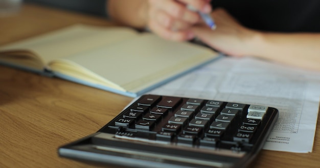 Kalkulator rąk i księgowy obliczający i pracujący w biurze rejestrują dane finansowe w miejscu pracy