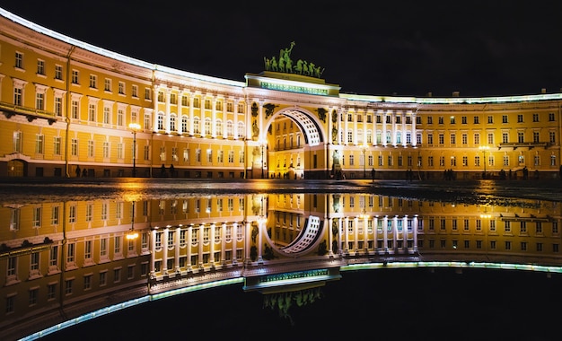 Kałuże na Placu Pałacowym i Newski Prospekt oświetlają nocą stare domy Sankt Petersburga.