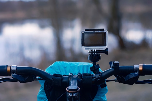Kamera akcji na rowerze z torbą rowerową w wodoszczelnym etui na tle rzeki.