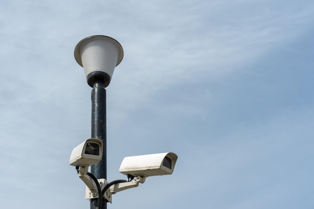 Kamery monitoringu zamontowane na latarni na tle błękitnego nieba Kamera monitoringu Bezpieczeństwo w mieście Ukryte filmowanie tego, co się dzieje Nowoczesne technologie i sprzęt