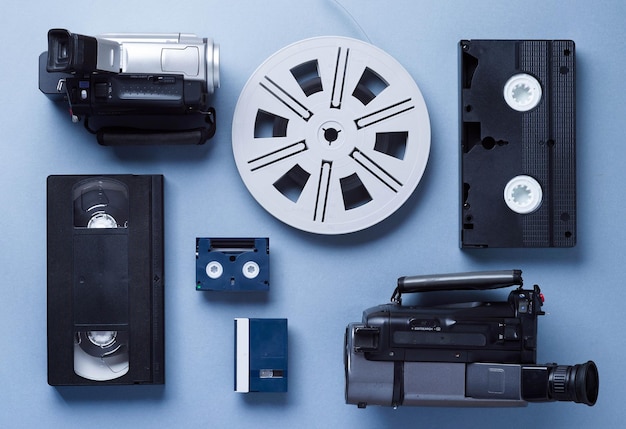 Zdjęcie kamery wideo kasety vhs i mini oraz rolka filmu dobrze ułożone na niebieskim tle nad widokiem
