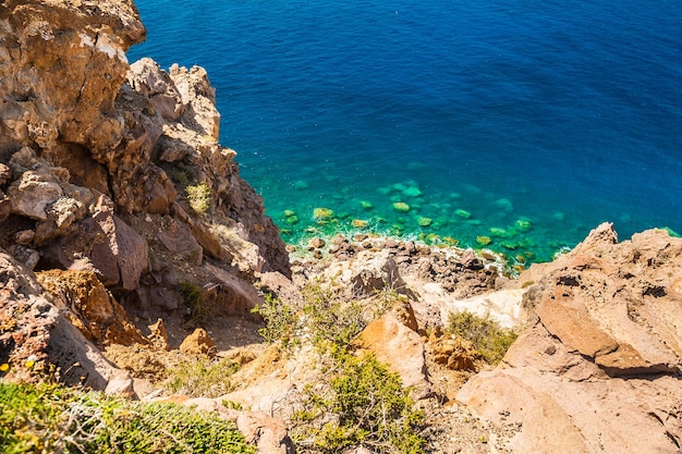 Kamienista plaża i czysta turkusowa woda morska. Piękny widok na wybrzeże. Wyspa Santorini, Grecja.