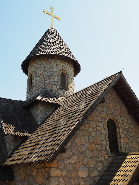 Kamienna cerkiew w etnoparku Turystyka religijna Budynek z kamienia z krzyżem na kopule Błękitne niebo