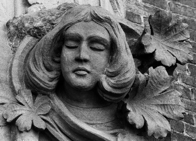Kamienna statua kobiety z zamkniętymi oczami.