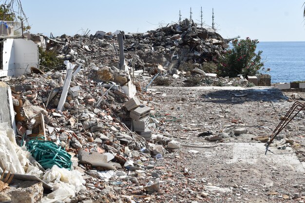 Kamienne ruiny zrujnowanego domu nad morzem. konsekwencje trzęsienia ziemi i tsunami. śmieci budujące góry