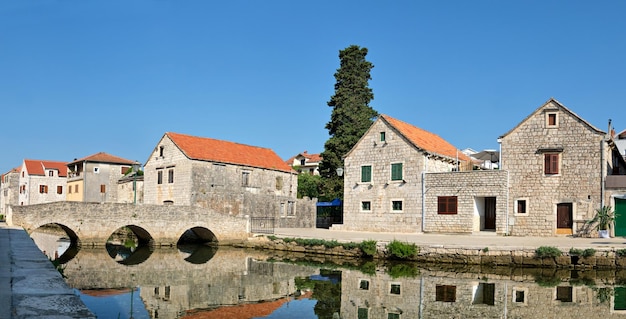 Kamienny most i stare zabytkowe domy w miejscowości Vrboska Wyspa Hvar Dalmacja Chorwacja Europa Panoramiczny obraz banera Stara atrakcja turystyczna wioski rybackiej