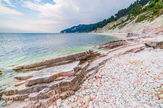 Zdjęcie kamyczki plaży kolorowe zatoki w parku przyrody conero dramatyczne wybrzeże cypel skała klif morze adriatyckie turystyka cel włochy turkus przezroczysta woda