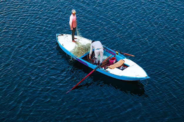 Kanał Sueski Egipt 11032022 Mała drewniana łódź na wodzie z rybakami przygotowującymi sieć