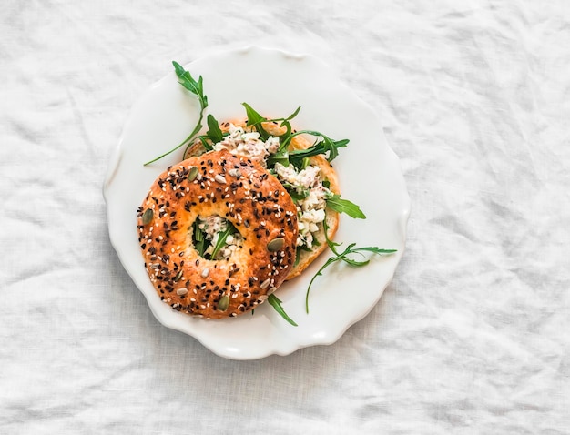 Kanapka z bagelami, sałatką z jajkami tuńczyka i arugulą, pyszna przekąska na śniadaniu na jasnym tle, widok z góry