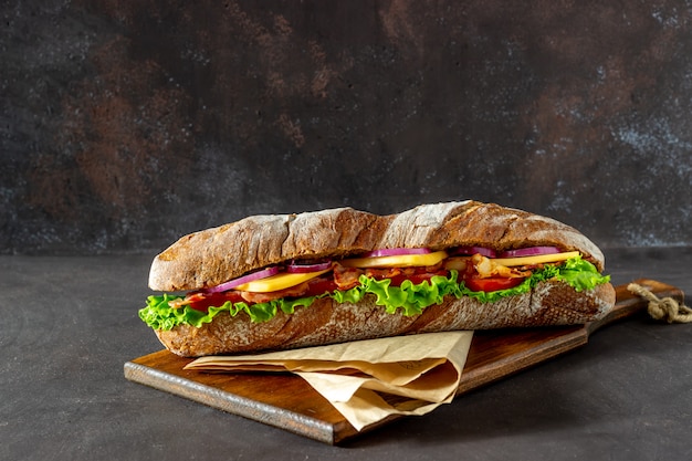 kanapka z ciemnego chleba z sałatką, boczkiem, pomidorami, serem i cebulą. Śniadanie. Fast food.