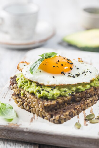 Kanapka z jajkiem awokado i szpinakiem na białym drewnianym tle zdrowa dieta śniadanie