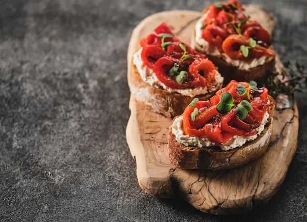 Kanapka z miękkim serem i pieczoną czerwoną papryką na drewnianej desce. Włoska bruschetta antipasti. Copyspace.