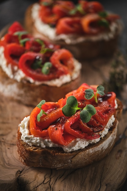 Kanapka z miękkim serem i pieczoną czerwoną papryką na drewnianej desce Włoskie antipasti bruschetta