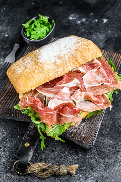 Kanapka Z Szynką Jamon Iberyjską Na Pieczywie Ciabatta. Czarne Tło. Widok Z Góry.