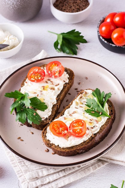 Kanapki na chlebie żytnim z pomidorami ricotta i pietruszką na talerzu na stole Widok pionowy