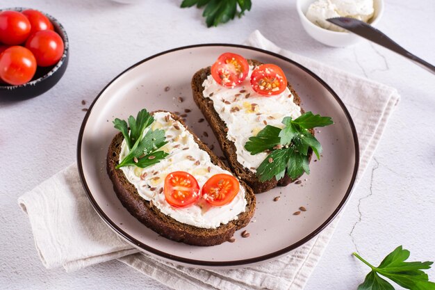 Kanapki na chlebie żytnim z pomidorami ricotta i pietruszką na talerzu na stole