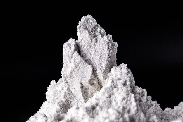 Kaolin na czarnej, odizolowanej, sproszkowanej powierzchni. Kaolin to minerał o budowie nieorganicznej