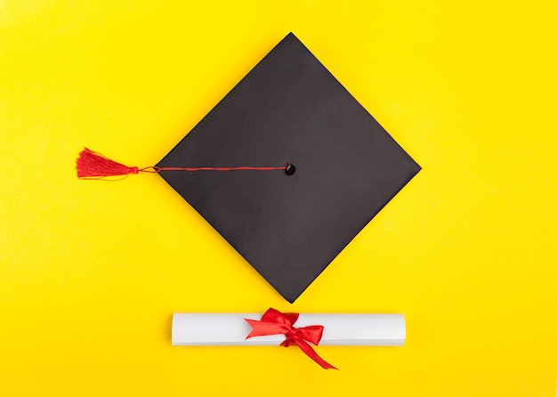 Kapelusz i dyplom ukończenia szkoły na żółtym tle
