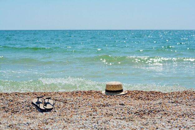 Zdjęcie kapelusz i klapki na piaszczystej plaży