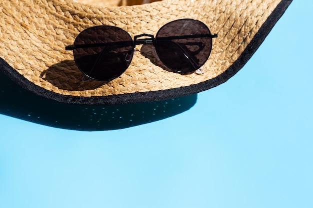 Kapelusz i okulary przeciwsłoneczni na błękitnym tle. Ciesz się koncepcją wakacji letnich.