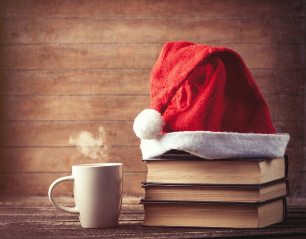 Kapelusz Mikołaja nad książkami przy filiżance gorącej kawy lub herbaty