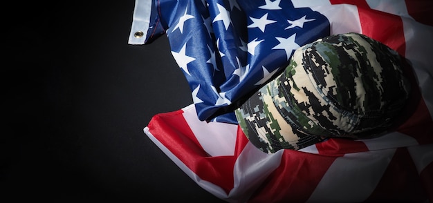Kapelusz wojskowy lub torba z amerykańską flagą. Kapelusz żołnierza lub hełm z amerykańską flagą narodową na czarnym tle. Reprezentuj koncepcję wojskową za pomocą obiektu kamuflażu i flagi narodowej USA.