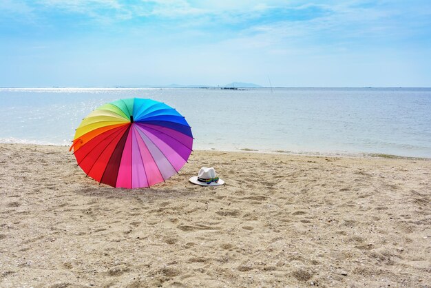 Kapeluszowe okulary przeciwsłoneczne i tęczowy parasol na tropikalnej plaży Pattaya Thailand
