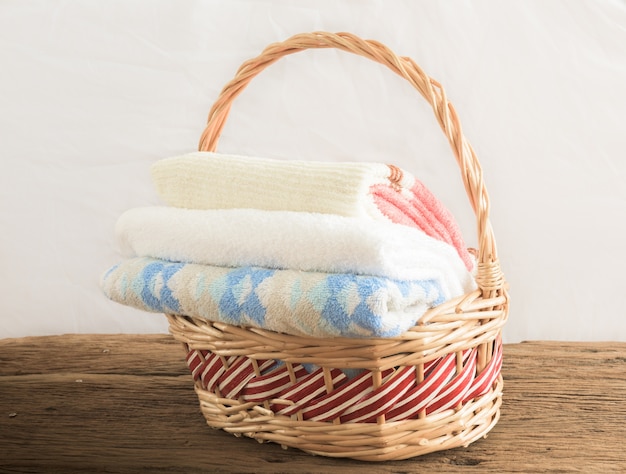 Kąpielowi ręczniki różni kolory w łozinowym koszu na drewnianym stole