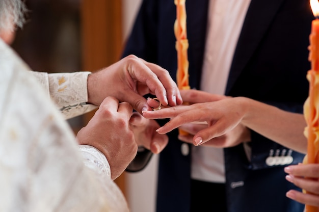 kapłan ubiera pierścienie dla nowożeńców.