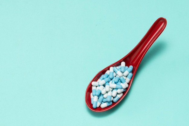 Zdjęcie kapsułki leków farmaceutycznych w plastikowej łyżce na kolorowym tle