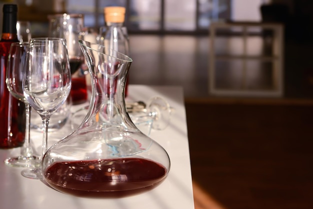 Karafka z czerwonym winem i kieliszkami na stole na niewyraźnym tle