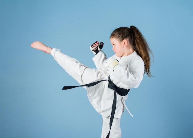 Karate daje poczucie pewności siebie. Silny i pewny siebie dzieciak. Jest niebezpieczna. Dziewczynka małe dziecko w białym kimono z paskiem. Zawodnik karate gotowy do walki. Koncepcja sportu karate. Umiejętności samoobrony.