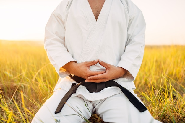 Karate mężczyzna siedzi na ziemi w polu