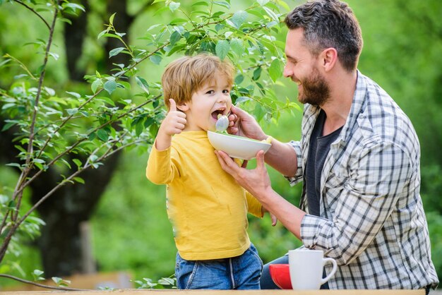 Karmienie dziecka Menu dla dzieci Rodzina spożywa domowy posiłek Ojciec syn je jedzenie i baw się Nawyki żywieniowe Jedzący mały chłopiec i tata Odżywianie dla dzieci i dorosłych Koncepcja zdrowego odżywiania