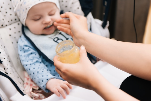 Karmienie. Urocze dziecko dziecko jedzenie z łyżką w krzesełko. Dziecko