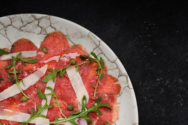 Karpaccio z łososia z kaprami, serem parmesanowym i rugalą