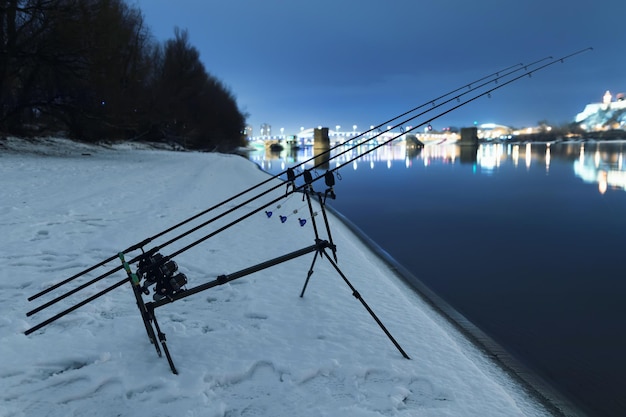 Karpiowe wędki spinning reel wędkarski w zimową noc. Nocne wędkowanie, wędki karpiowe, wędkarstwo zimowe.