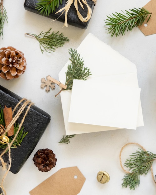 Karta papierowa między dekoracją bożonarodzeniową, czarnymi pudełkami z prezentami i zielonymi gałęziami jęczmienia, widok z góry, poziomy