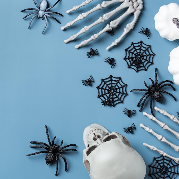 Karta powitalna na Halloween z czaszkami dyni, kościstymi rękami i liśćmi.
