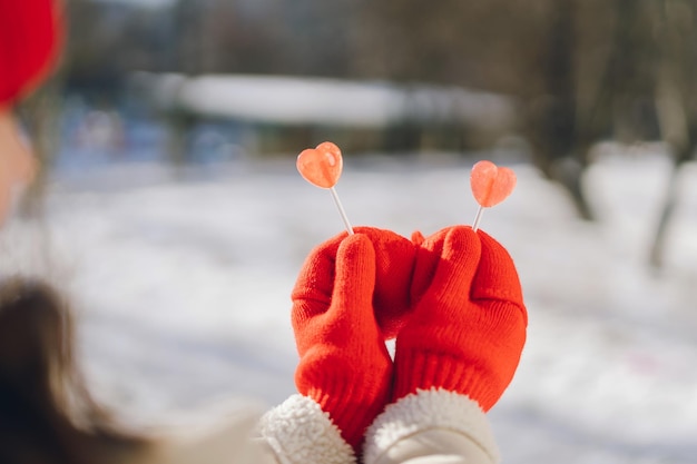 Karta walentynkowa kobieta w czerwonych rękawiczkach trzymająca dwa lizaki w kształcie serca kocham cię