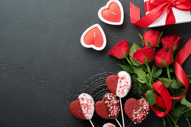 Karta walentynkowa Różowe czerwone kwiaty ciasteczka brownie i cukierki czekoladowe na pudełku w kształcie serca z winem na czarnym tle Kartkę z życzeniami z okazji Dnia Matki lub Kobiet Widok z góry leżał płasko