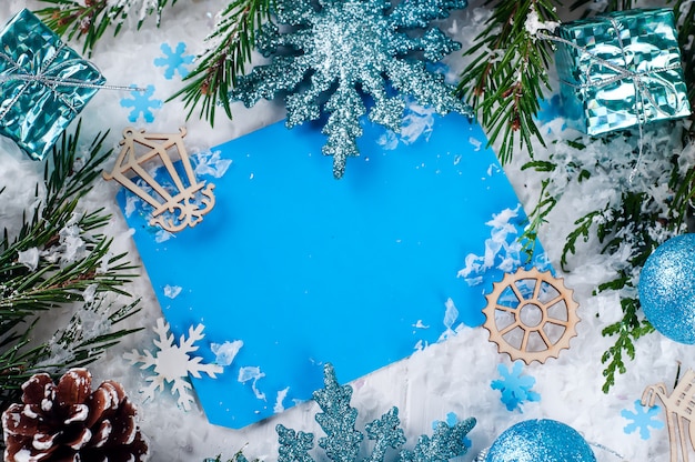 Kartka bożonarodzeniowa z dekorującym jedlinowym drzewem na śniegu.