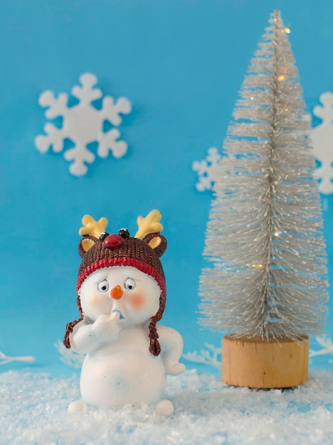 Kartka świąteczna, miejsce do kopiowania. Zabawny bałwan stojący w zimowym krajobrazie Bożego Narodzenia. Na jasnym niebieskim tle. Świąteczny tło z śmiesznym bałwanem. Kartkę z życzeniami szczęśliwego nowego roku. wersja pionowa.