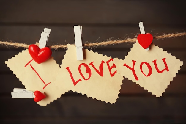 Kartka walentynkowa z sercami i słowami miłości na drewnianym tle