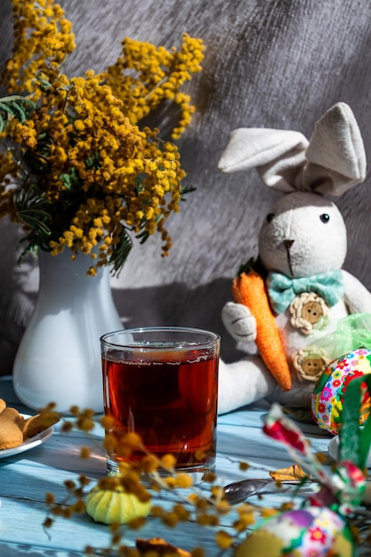 Kartka wielkanocna Gorący napój w szklance wesoły króliczek z marchewką Świąteczne kolorowe jajka mimoza