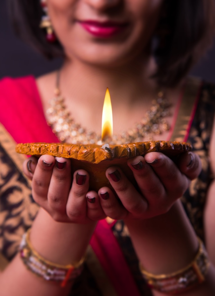 Zdjęcie kartka z życzeniami happy diwali przedstawiająca indyjską piękną dziewczynę trzymającą lampę naftową diya lub terakotową na czarnym tle